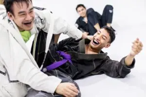 Two BJJ practitioners laughing and enjoying a training session at Alpha Jiu Jitsu Academy, highlighting camaraderie and fun in practice.