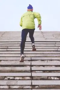 Athlete running up stairs outdoors as part of a training routine, emphasizing endurance, strength, and fitness.