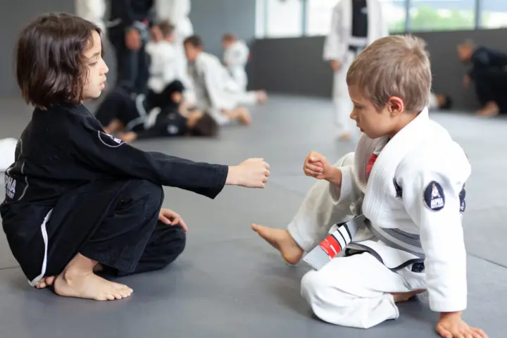 Two young students at Alpha Jiu Jitsu Academy sharing a fist bump during a BJJ class, highlighting camaraderie and sportsmanship.