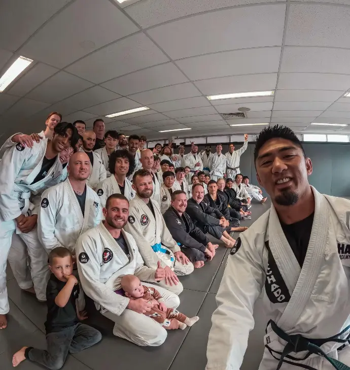 Group of Brazilian Jiu Jitsu students and instructors at Alpha Jiu Jitsu Academy posing for a photo after a training session, showcasing community and camaraderie.