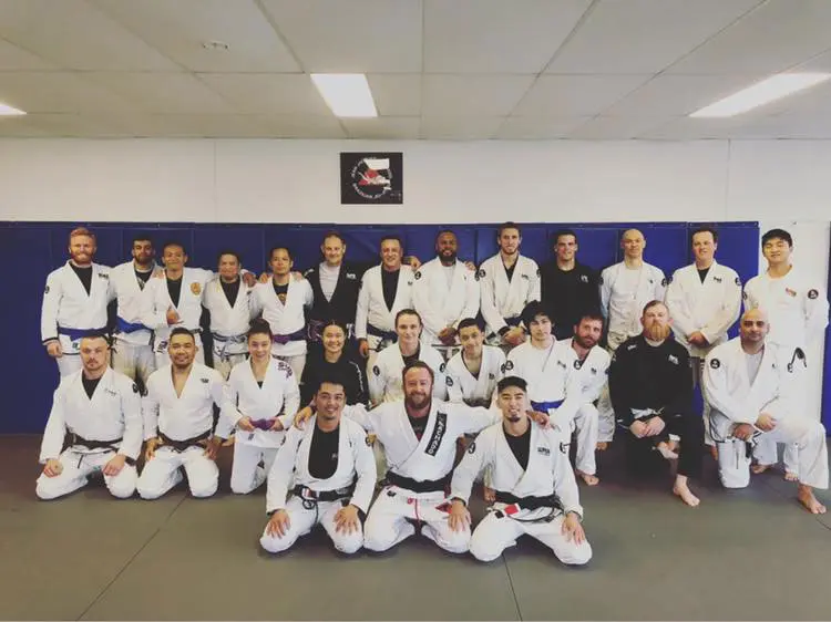 Large group of Brazilian Jiu Jitsu students and instructors posing together after training at Alpha Jiu Jitsu Academy, showcasing teamwork and dedication.