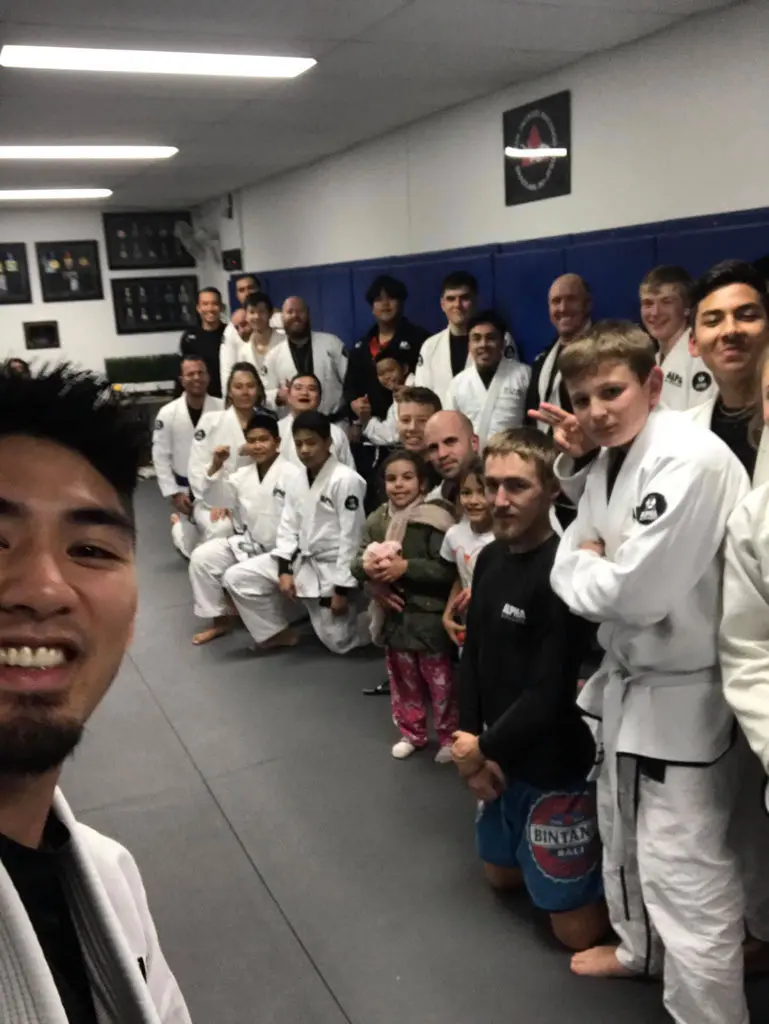 Group photo of Alpha Jiu Jitsu Academy students and instructors smiling after a class session, led by Professor Xavier Sales.