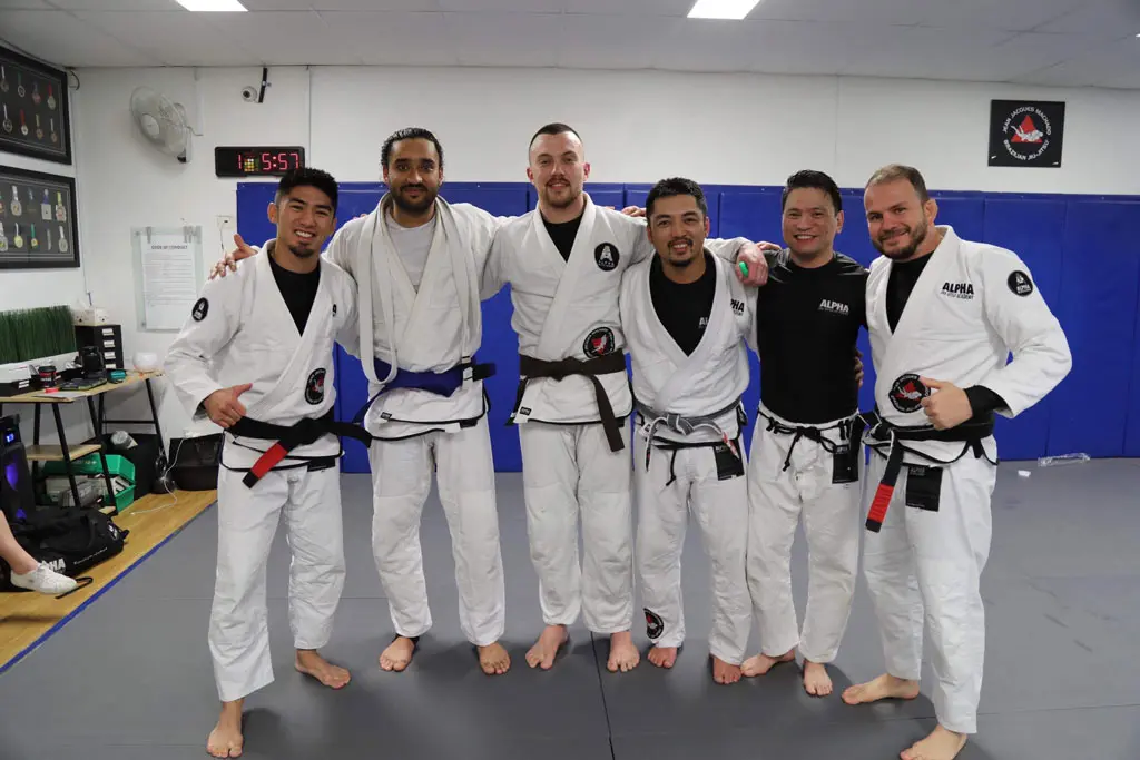 Alpha Jiu Jitsu Academy instructors posing together after a Brazilian Jiu Jitsu training session, showcasing camaraderie and expertise in martial arts training.